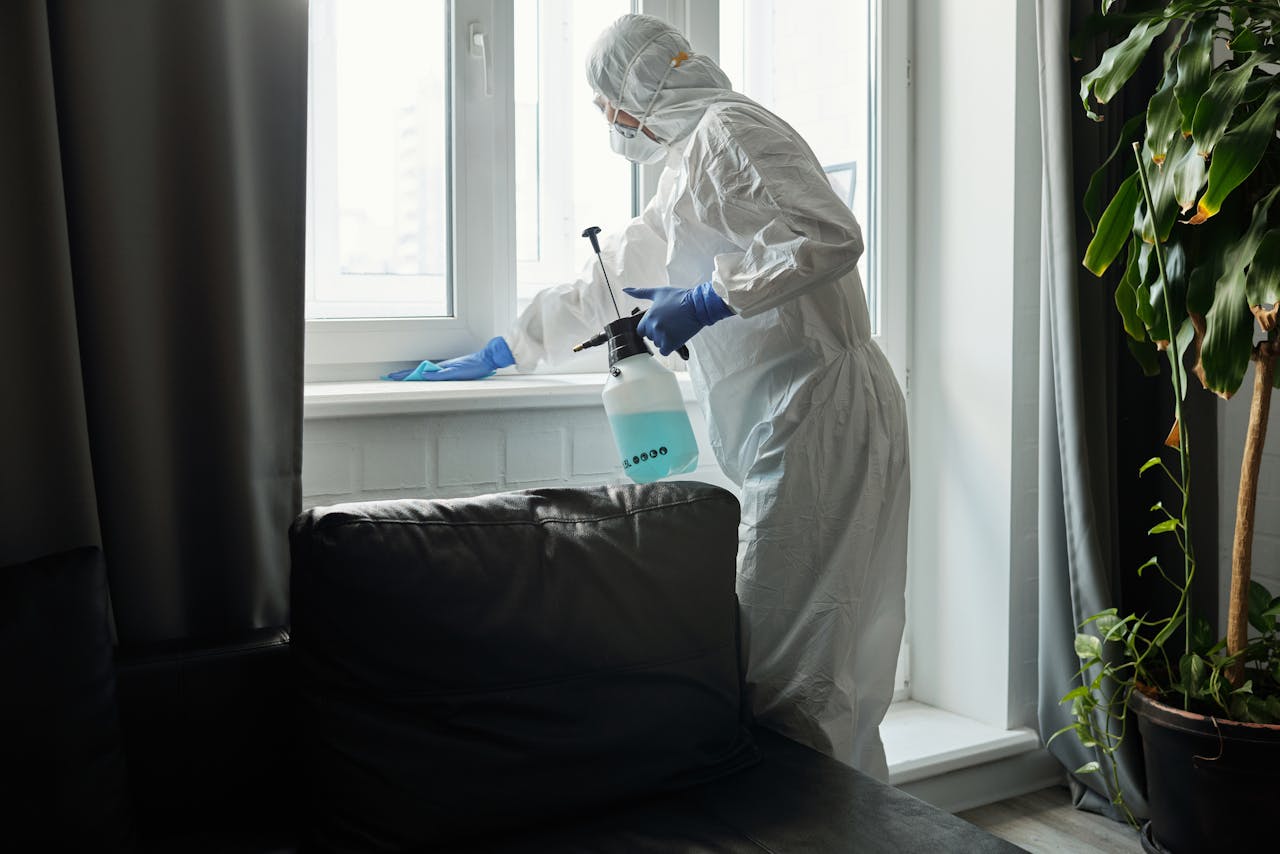 hero-img-02 Person in PPE disinfecting indoor window area during COVID-19 pandemic.